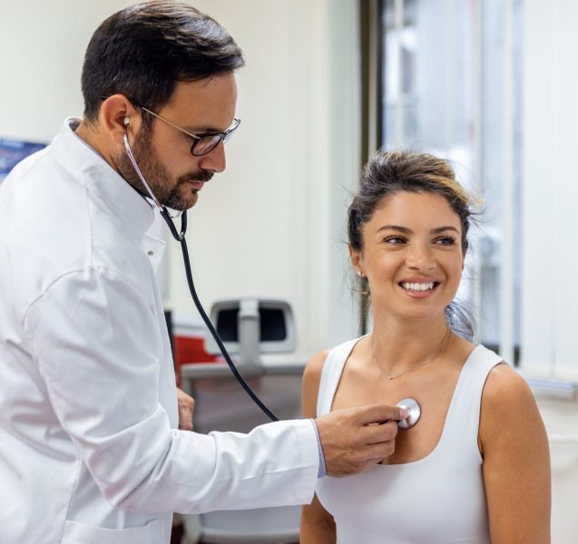 Young doctor listen to female patient heart chest with stethoscope at clinic meeting. Man GP checkup examine woman client with phonendoscope. healthcare concept.